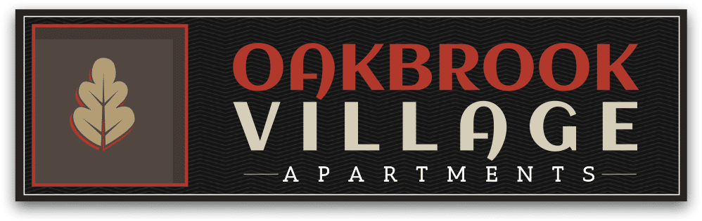 A rectangular sign with a beige leaf graphic and the text "Oakbrook Village Apartments" in red and beige on a black patterned background.