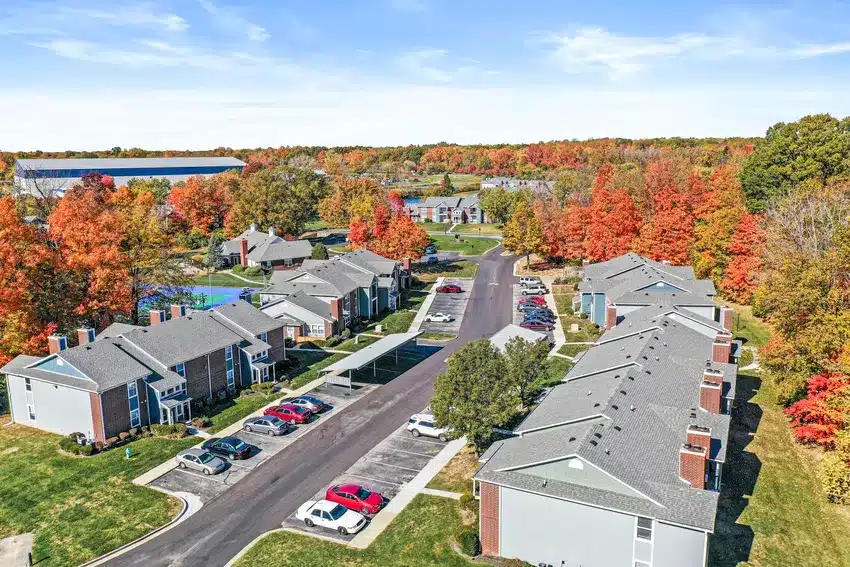 Aerial view of an apartment complex with parked cars and autumn-colored trees lining the streets.